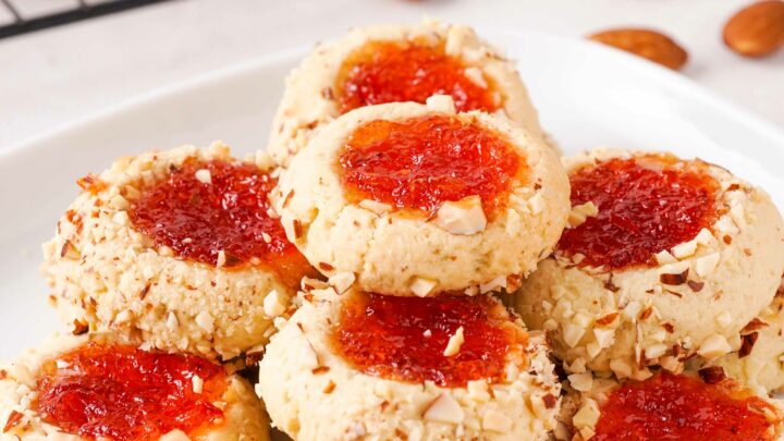 Gluten-free thumbprint cookies stacked on a white plate.
