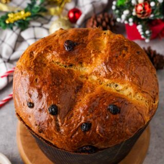 Gluten-Free Panettone on a brown board with festive decorations around it.