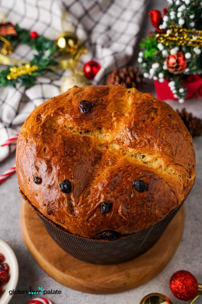 Gluten-Free Panettone on a brown board with festive decorations around it.