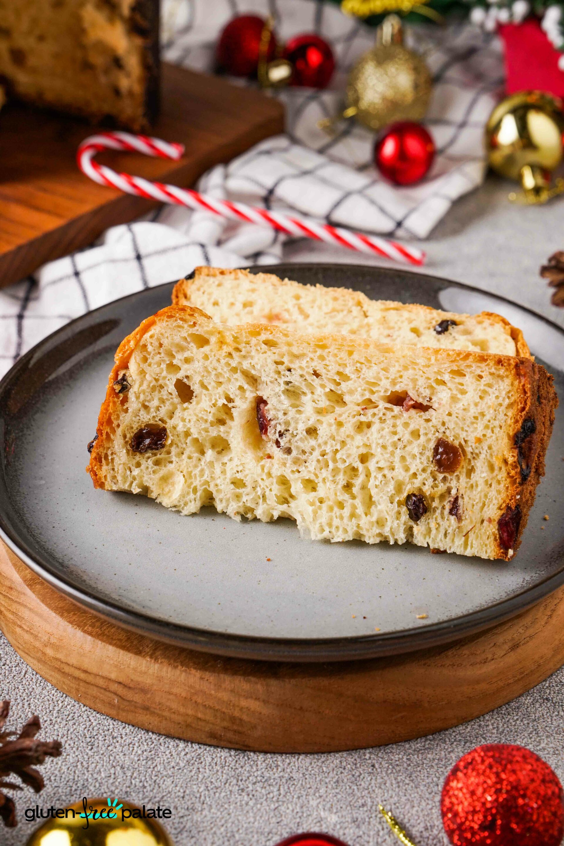 Gluten-Free Sliced Panettone on a brown board with festive decorations around it.