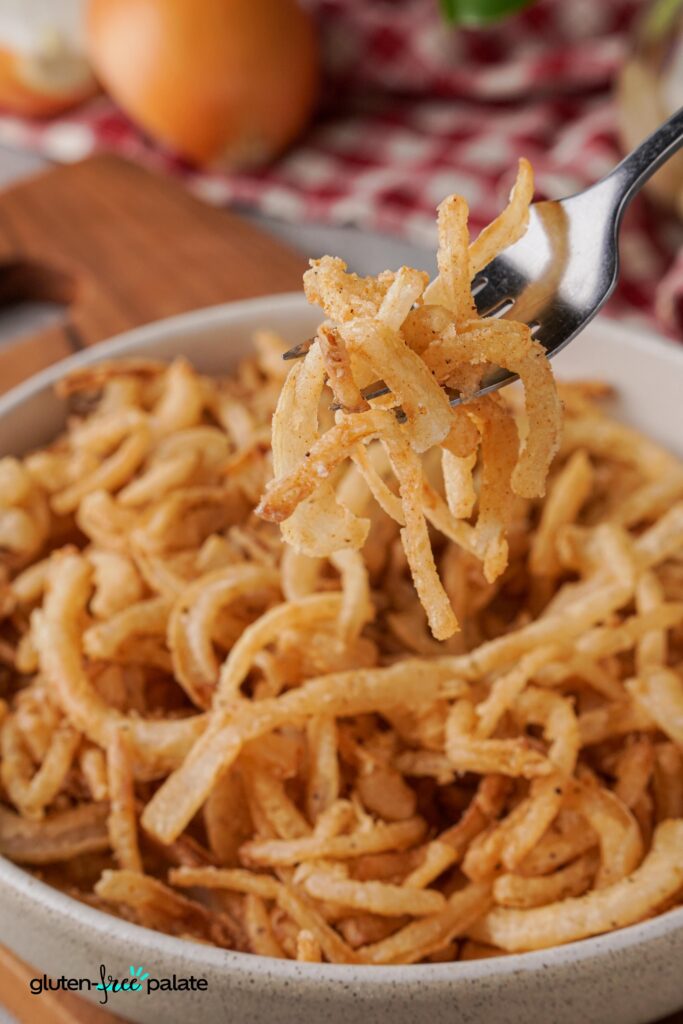Close up view of Gluten-free fried onions on a fork from a bowl. 
