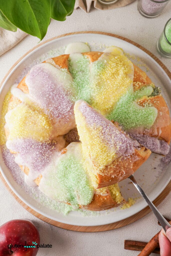 Gluten-Free King Cake top view with colored sugar and a cut slice.