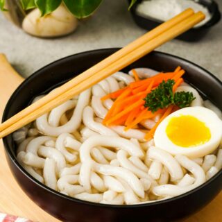 Gluten-Free Udon Noodles in a black bowl with chopsticks.