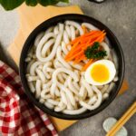 Gluten-Free Udon Noodles in a black bowl with chopsticks.