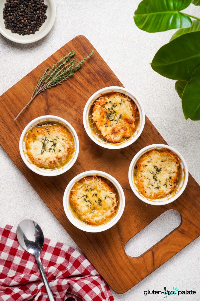 Gluten-Free French onion soups in a white ramekins on a wooden board.