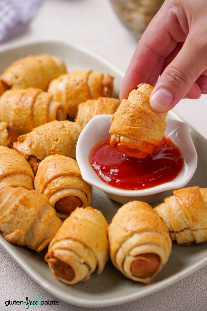 Gluten-Free pigs in a blanket being dipped into ketchup.