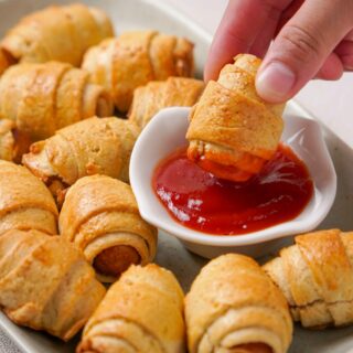 Gluten-Free pigs in a blanket being dipped into ketchup.