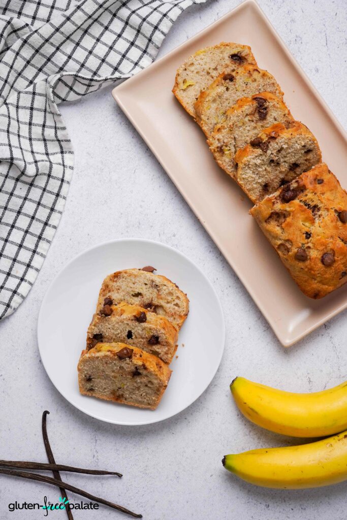 Sliced gluten-free banana bread on a side plate next to the full loaf, made with certified gluten-free butter