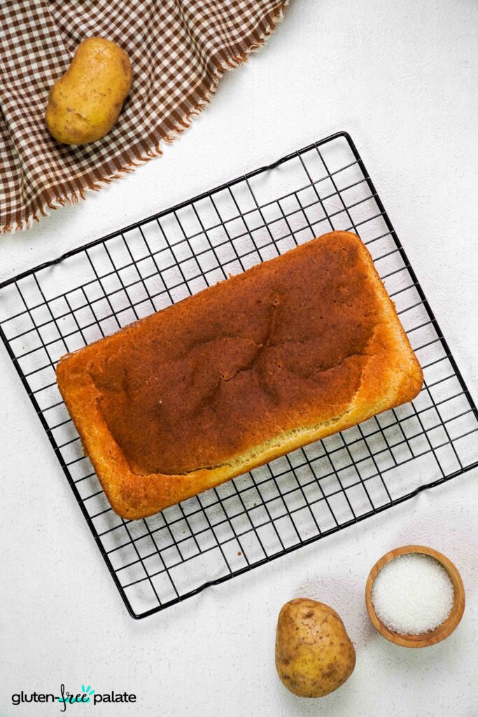 A loaf of Gluten-free potato bread on a cooling rack.