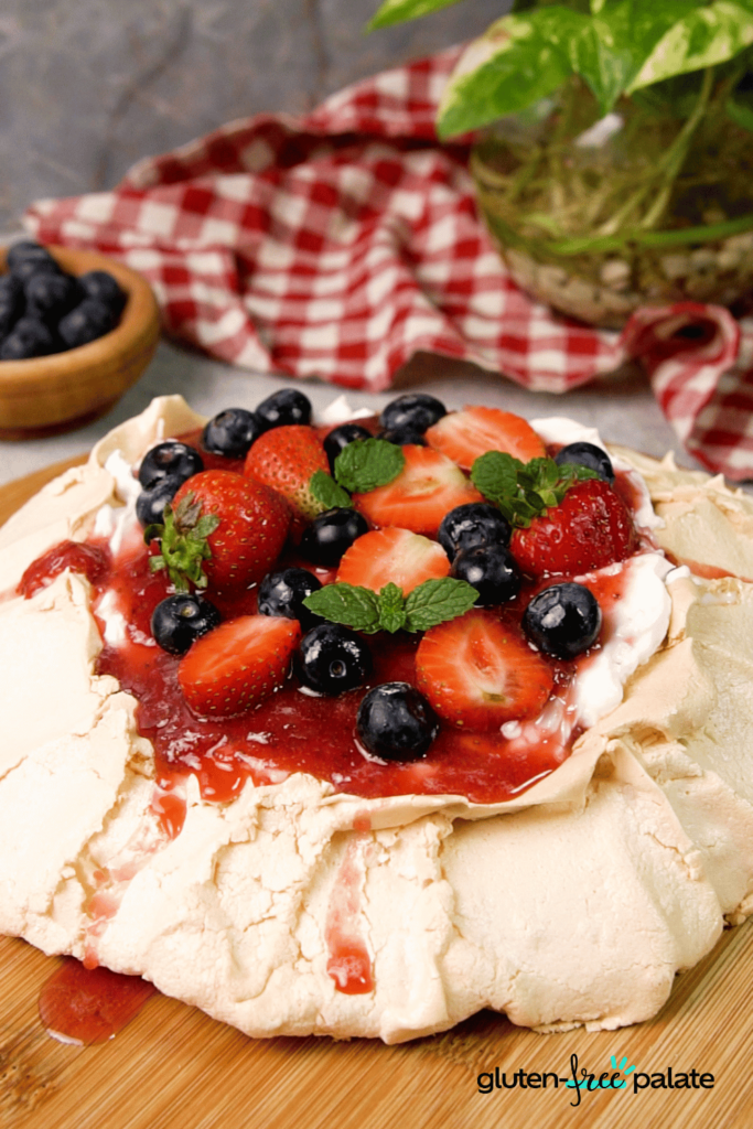 Finish the pavlova recipe by adding fresh fruit, strawberry sauce, and fresh mint leaves.