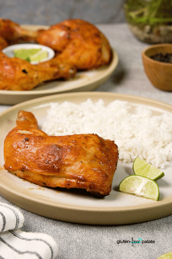 Tandoori chicken on a plate with rice and two slices of lime, a classic turmeric recipe.