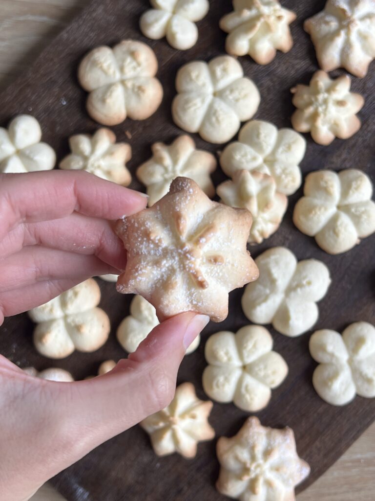 A spritz cookie in a persons hand.
