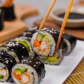 Sushi being lifted from a plater with chopsticks. Photo and recipes by Gluten-Free Palate.