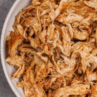 A bowl filled with cooked and shredded barbecue chicken.