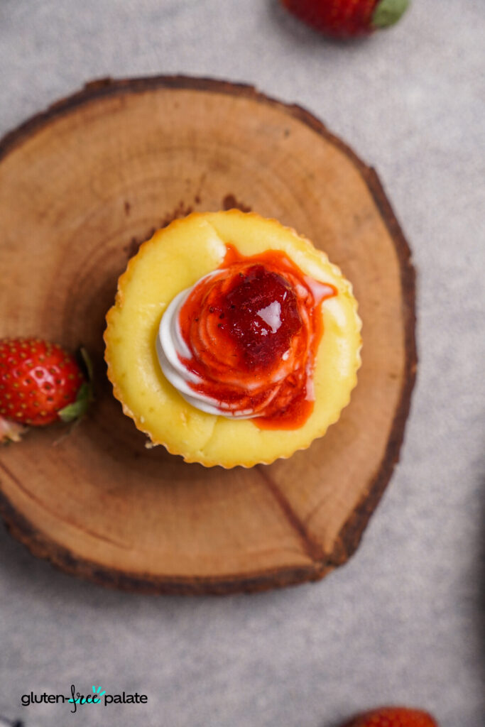 A single mini gluten-free cheesecake bite with a rich, creamy texture, topped with strawberry sauce.