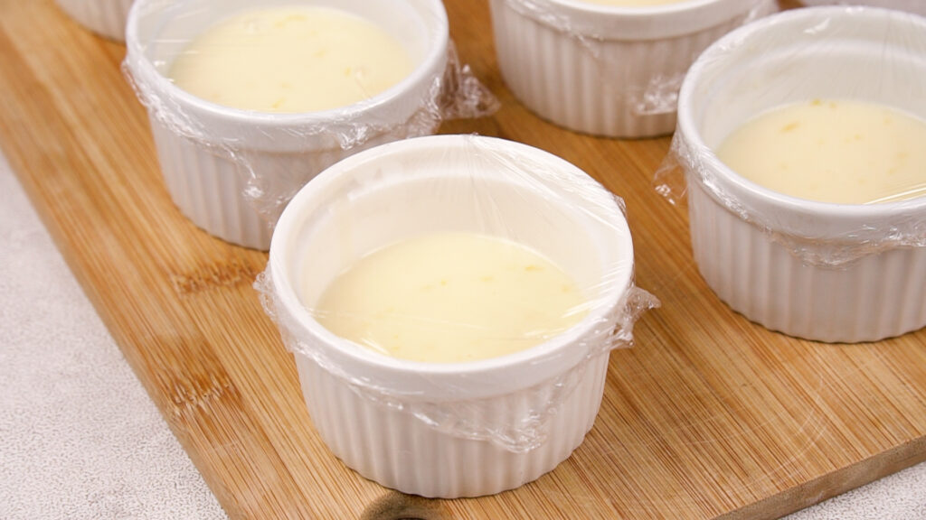 Each ramekin is covered with plastic wrap, ready to be chilled in the refrigerator until set.