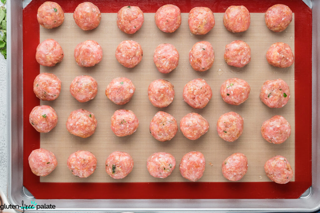 Raw gluten-free turkey meatballs on a baking tray.