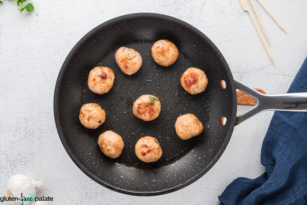 Cooked meatballs in a frying pan.