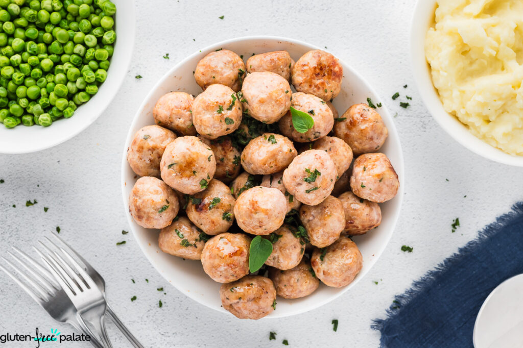 A bowl of gluten-free meatballs with garnish.