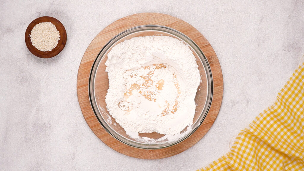 The flour mixture in the glass bowl is partially combined, showing the first stage of blending the dry ingredients for the gluten-free cracker dough.