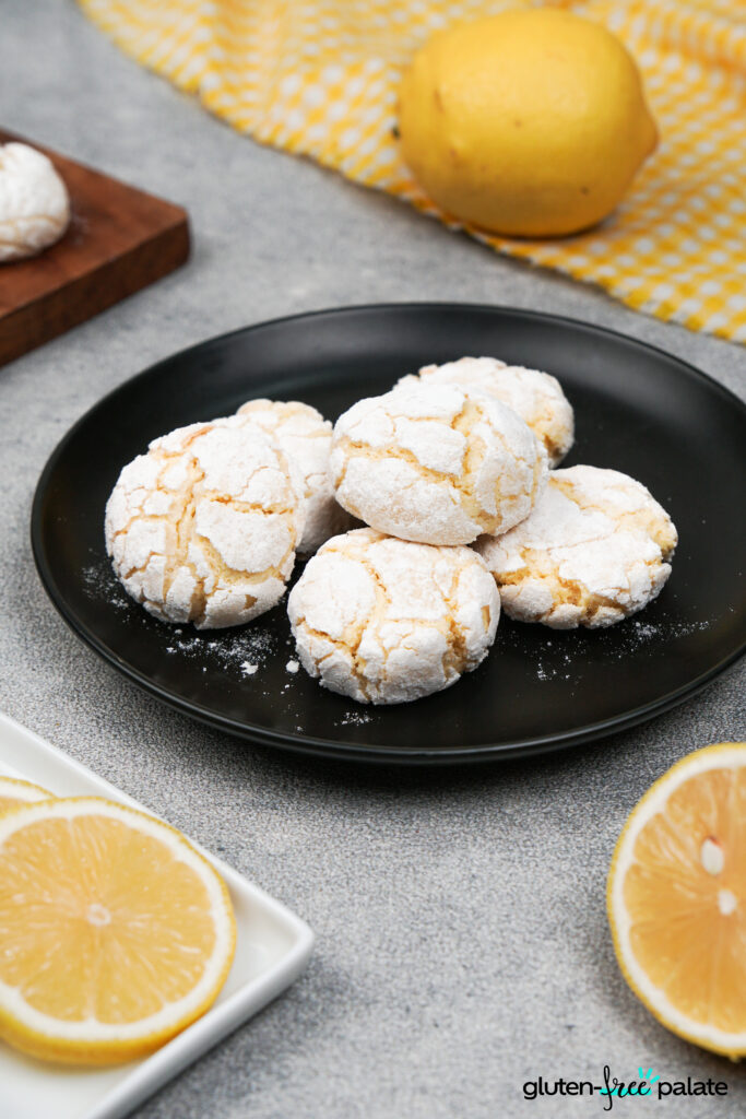 Gluten-Free Lemon Crinkle Cookies on Black Plate with Fresh Lemons