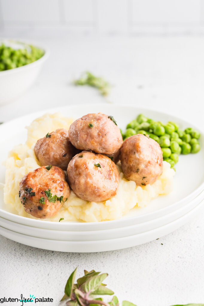 A plate of meatballs, mash and peas.
