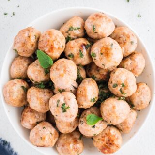 Gluten-free meatballs in a white bowl with garnish.