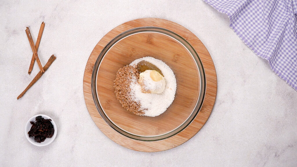 A mixing bowl with butter, brown sugar, and granulated sugar sitting on a wooden trivet.