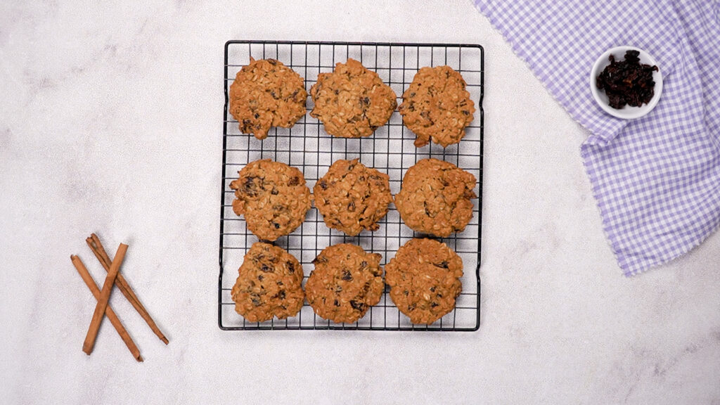Baked cookies cooling on a wire rack, golden brown and slightly cracked.