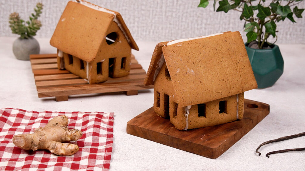Assembled gluten-free gingerbread houses with royal icing holding the pieces together, displayed on wooden boards.