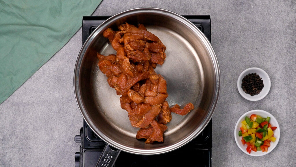 Seasoned raw chicken in a skillet with oil.