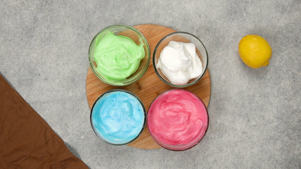 Bowls of green, blue, pink, and white whipped cloud bread batter ready to be shaped and baked.