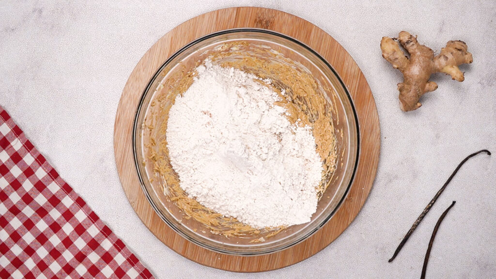 Flour mixture being added to the wet ingredients in a mixing bowl.