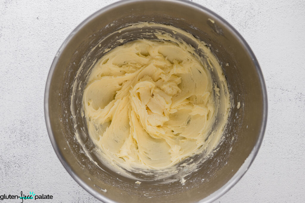 Finished creamy, fluffy gluten-free buttercream frosting whipped in a stainless-steel mixing bowl.
