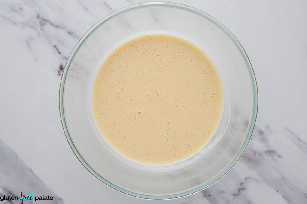 Glass bowl showing combined wet mixture for mochi waffle batter.