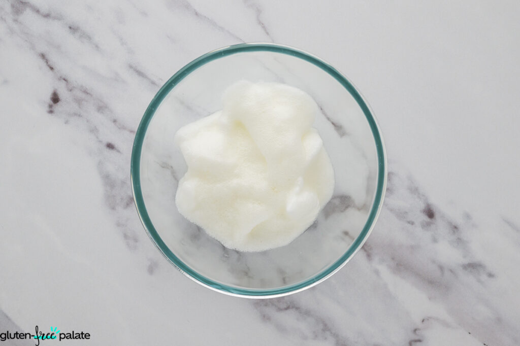 Egg white whipped to soft peaks in a clear mixing bowl.
