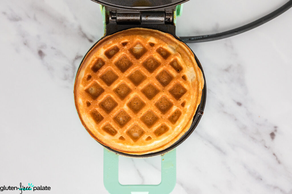 Golden brown mochi waffle just cooked in the waffle maker, crisp on the outside with defined grid marks.