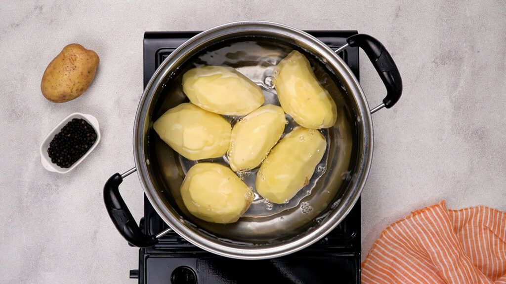 Peeled Yukon gold potatoes boiling in a pot of water.
