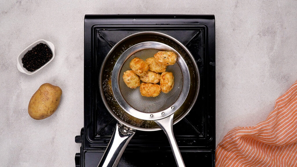 Gluten-free tater tots frying in hot oil until golden and crispy.