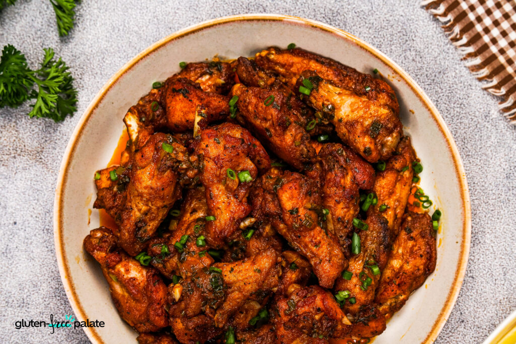 Golden brown cowboy butter chicken wings coated in smoky butter sauce, served in a ceramic bowl and garnished with green herbs.