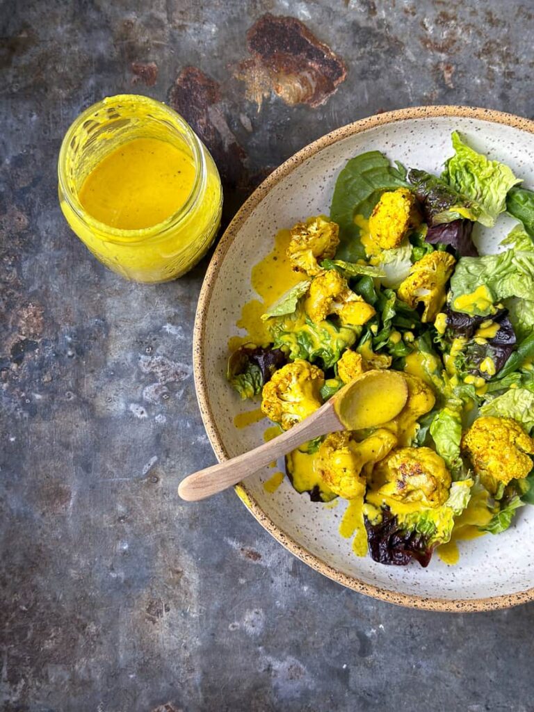 Turmeric tahini dressing in a jar with a salad. Photo by marinmamacooks.com.