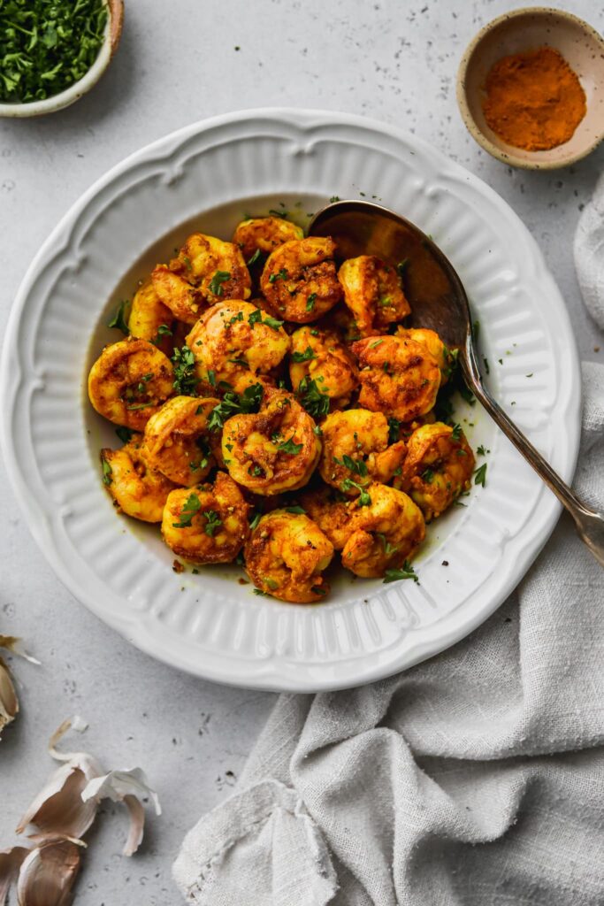 Turmeric Shrimp With Cumin & Garlic in a white plate. Photo by
walderwellness.com