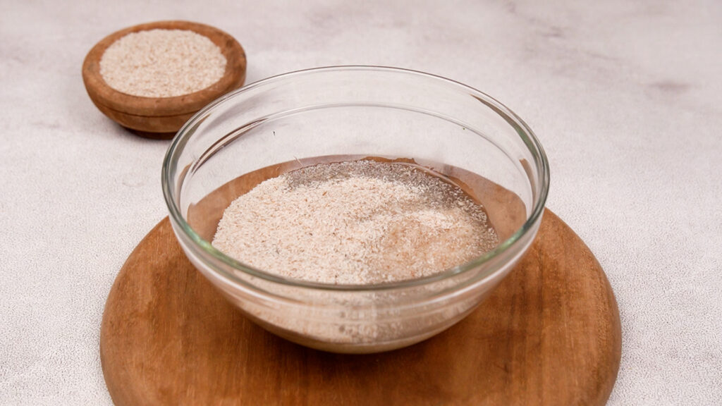 A glass bowl with psyllium husk soaking in water, forming a gel for gluten-free ciabatta dough.