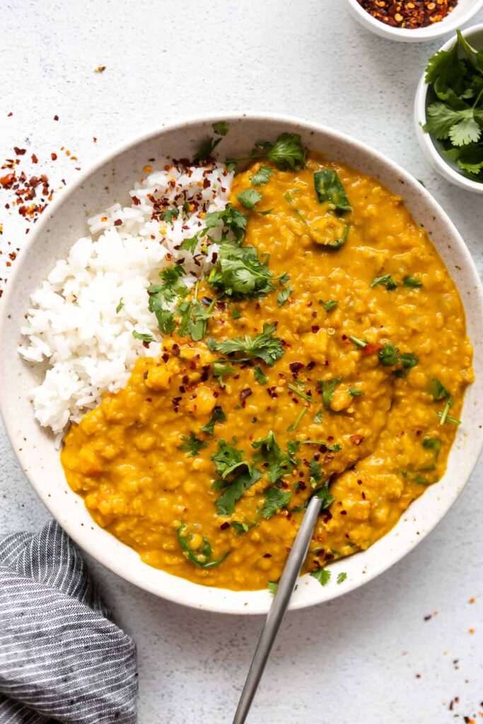 Red lentil dahl in a white plate. Photo by eatwithclarity.com.