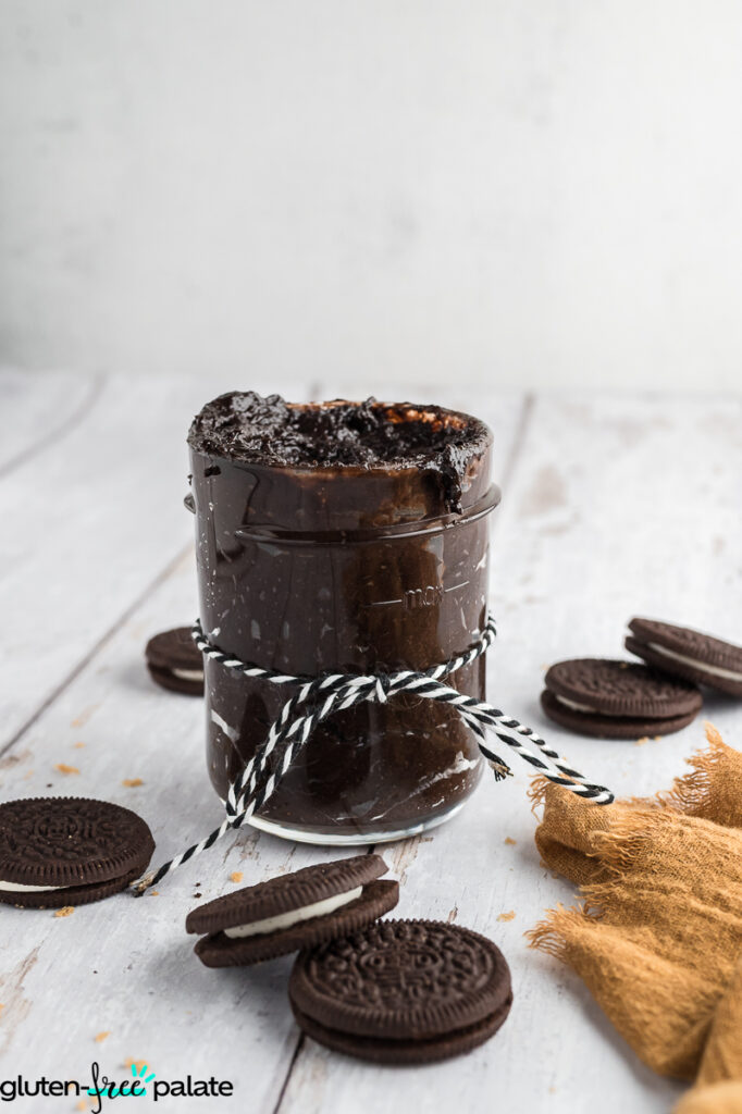 A jar of Oreo cookie butter tied with string surrounded by cookies.
