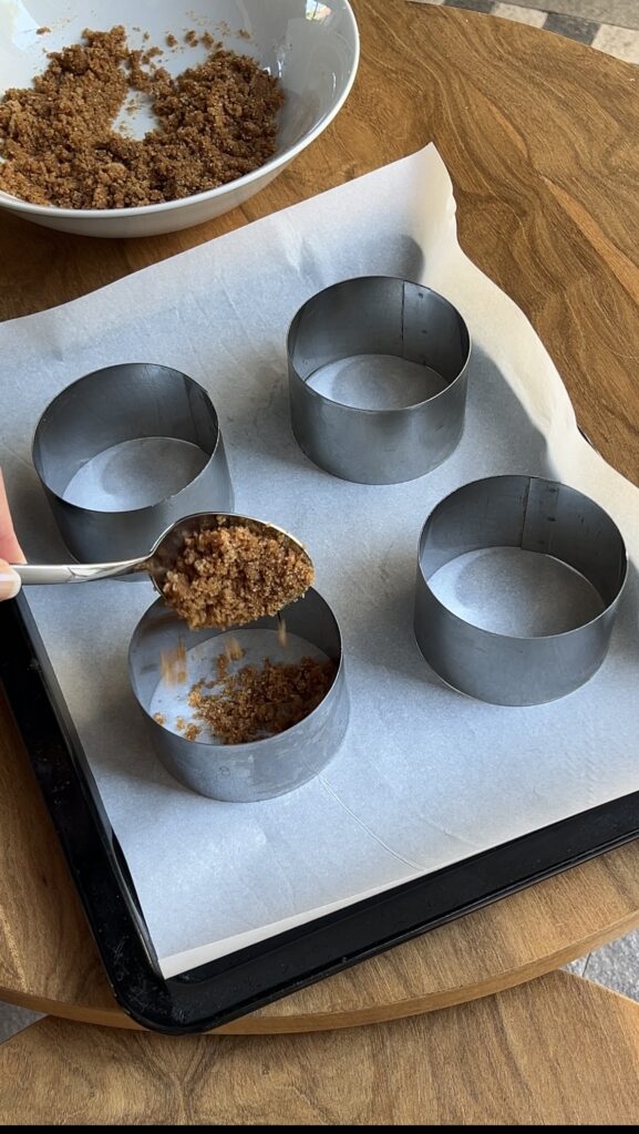 Biscuit base being poured into round cookie cutter.