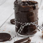Jar of Oreo cookie butter tied with string surrounded by cookies.