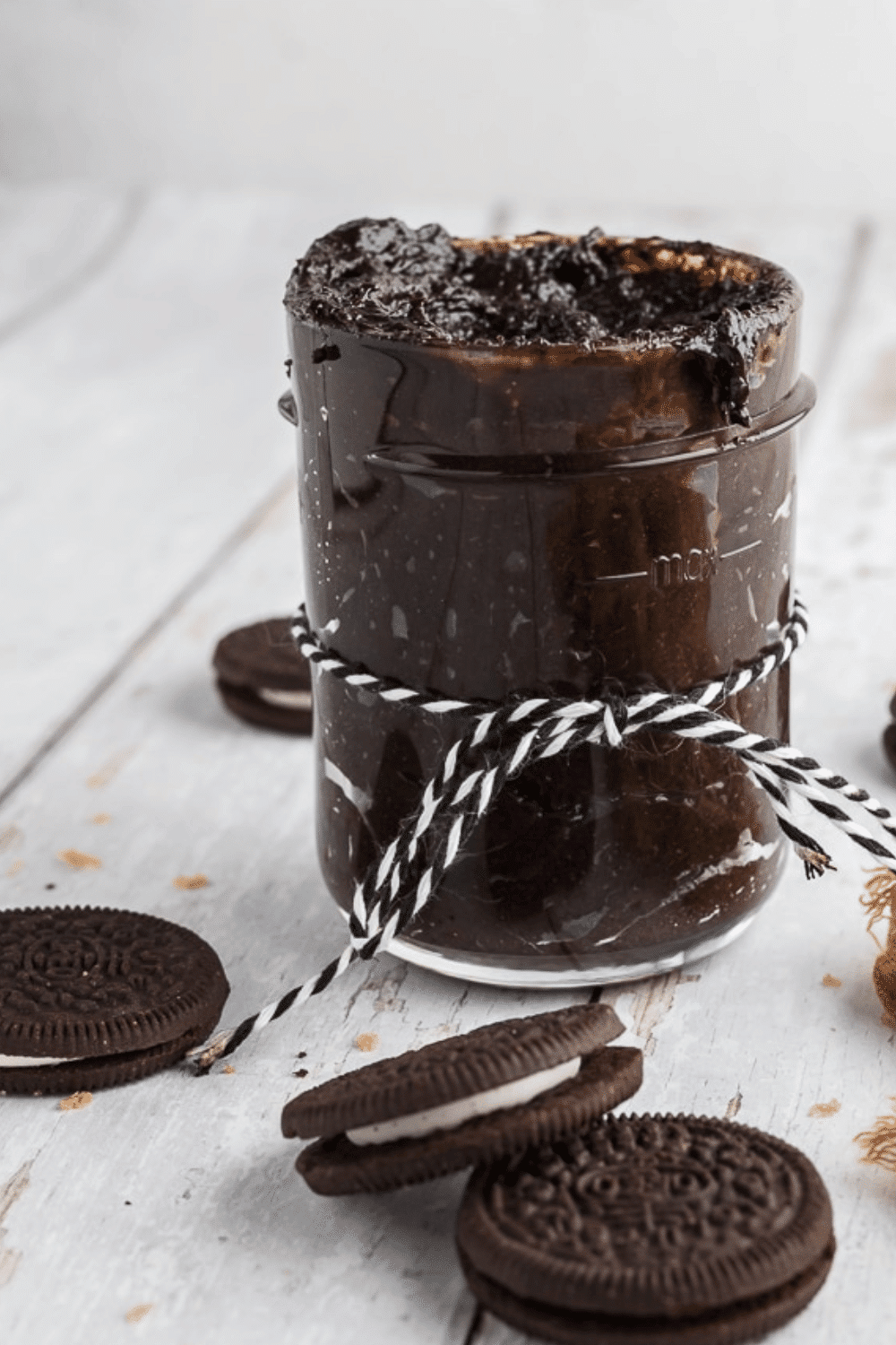 Jar of Oreo cookie butter tied with string surrounded by cookies.