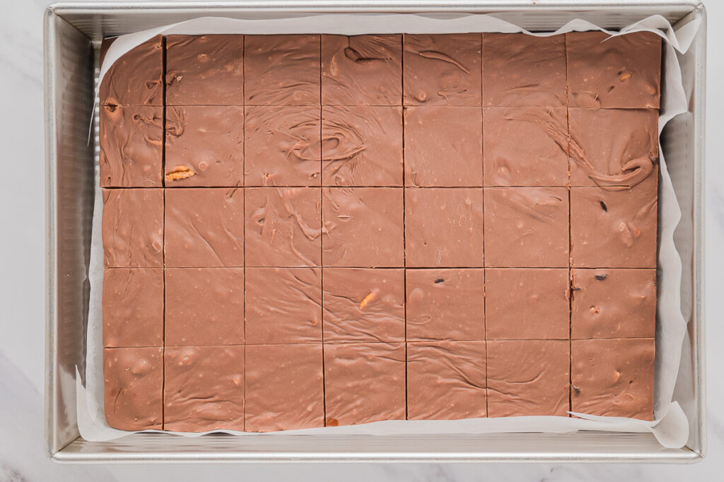 Fudge set in baking pan with parchment papeer.