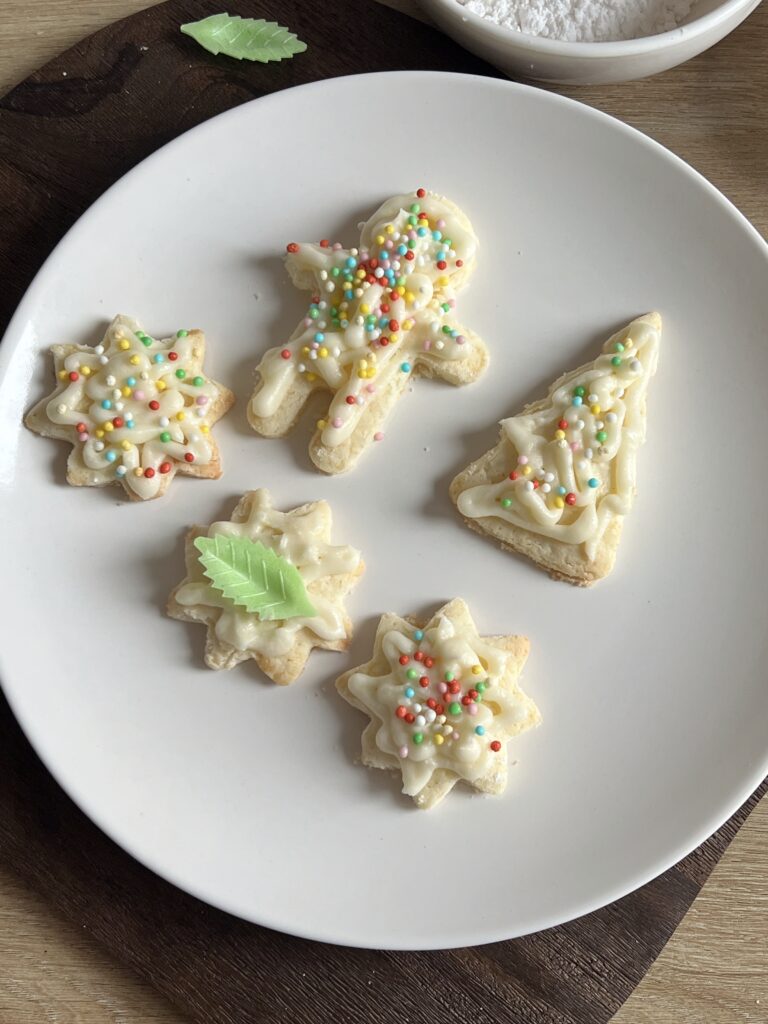 A distant shot of a plate of Christmas Sugar Cookies cut in different shapes.